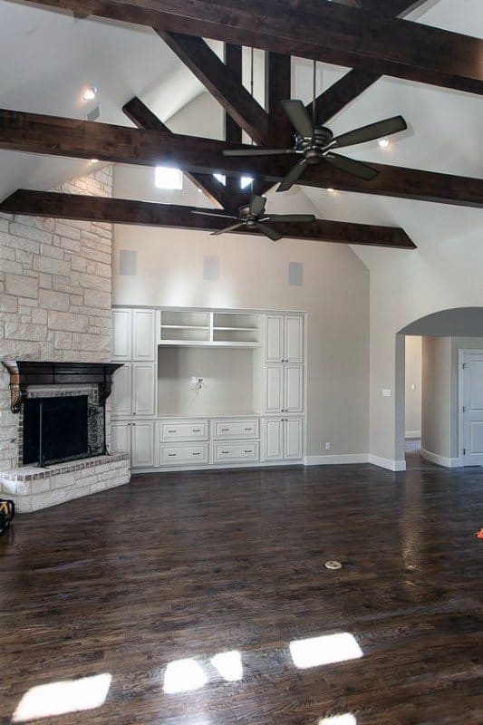 Spacious living room with stone corner fireplace, dark wood beams, and built-in white cabinetry.