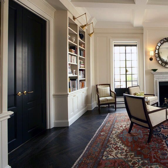 Traditional living room with floor-to-ceiling built-in bookcases, dark wood floors, vintage rug, and elegant furnishings