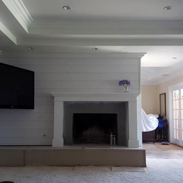 This living room features a striking trey ceiling with well-defined crown molding, complementing the clean and rustic look of shiplap walls. The minimalist decor and soft lighting accentuate the modern aesthetic of the room