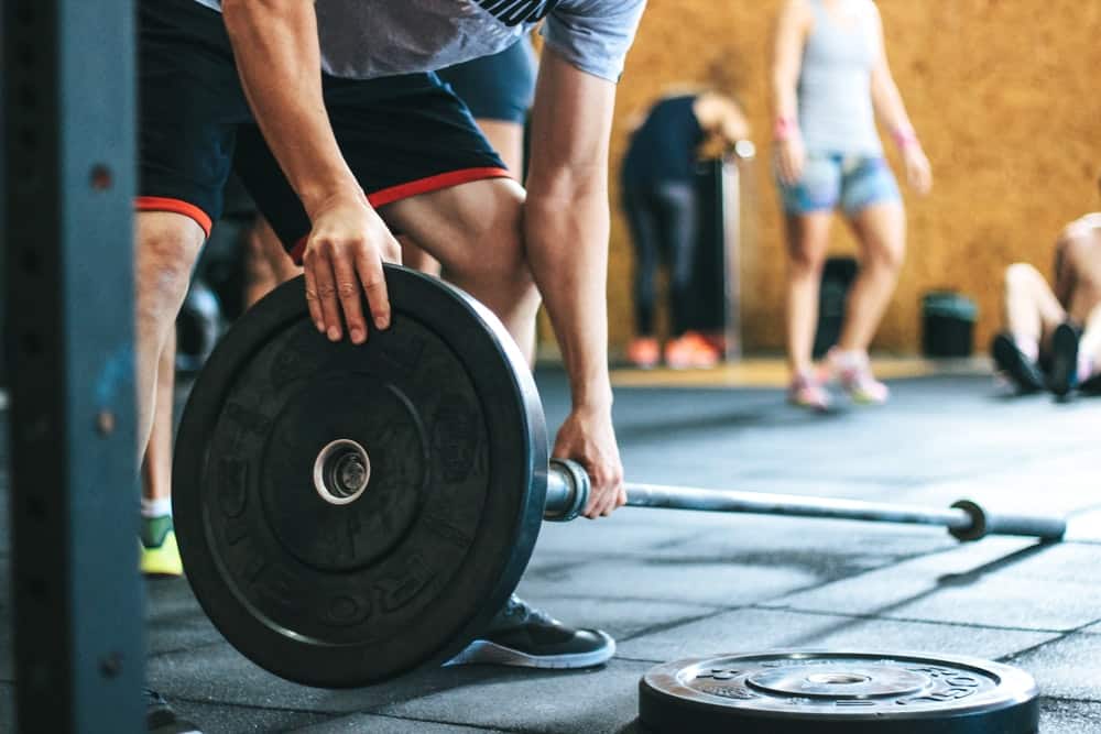 an athlete loads up a barbell with weight in a gym