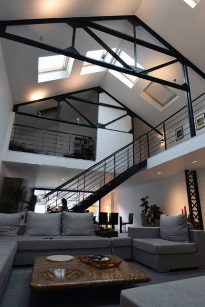 Modern loft with sleek metal beams, skylights, and minimalist furniture.