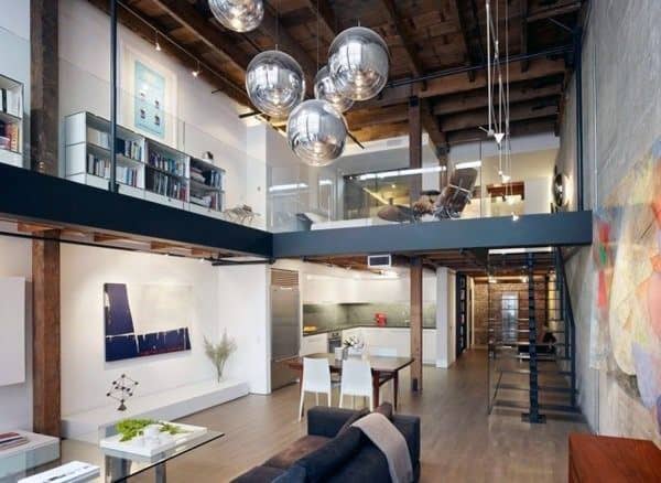 Modern loft with glass railing, exposed beams, open layout, and reflective pendant lights.