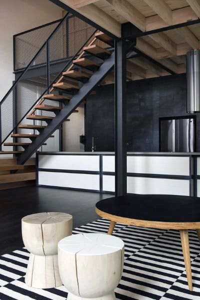 Industrial loft with black metal staircase, wooden accents, and striped rug decor.