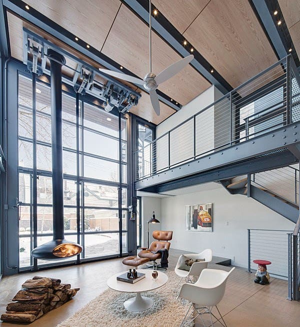 Modern industrial loft with high ceilings, large glass windows, and a suspended fireplace.