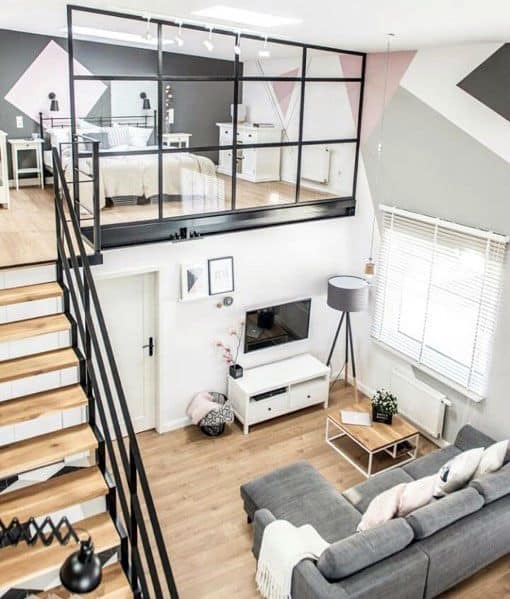 Loft-style studio with modern staircase, glass railing, cozy living area, and colorful accents.