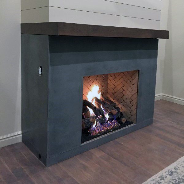 Compact concrete fireplace with a wooden mantel and herringbone brick interior, showcasing a warm, burning log fire.