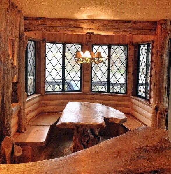 Rustic wooden dining nook featuring a unique table and bench seating by windows with diamond-patterned panes