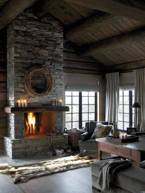 Log cabin living room with stone fireplace, wooden beams, cozy furniture, and warm lighting.