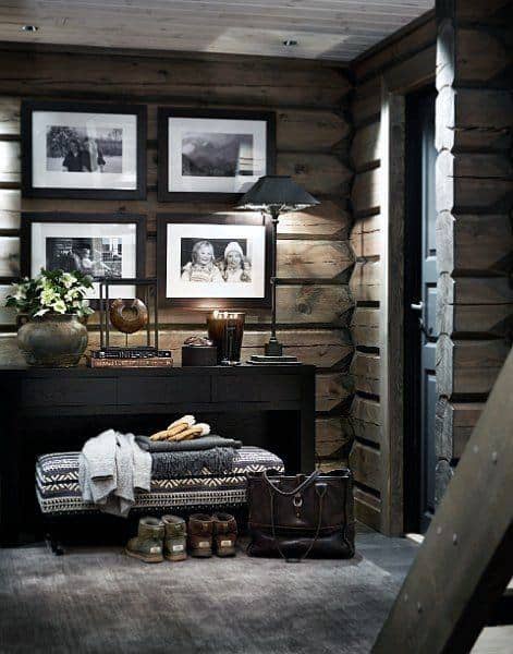 Cozy log cabin entryway with framed photos, rustic decor, and warm lighting.