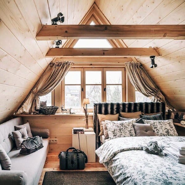 Cozy attic bedroom in a log cabin with wooden beams, soft bedding, and natural light.