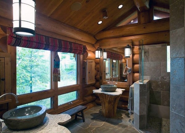 Rustic log cabin bathroom with large windows, stone sink, wooden touches, and natural light