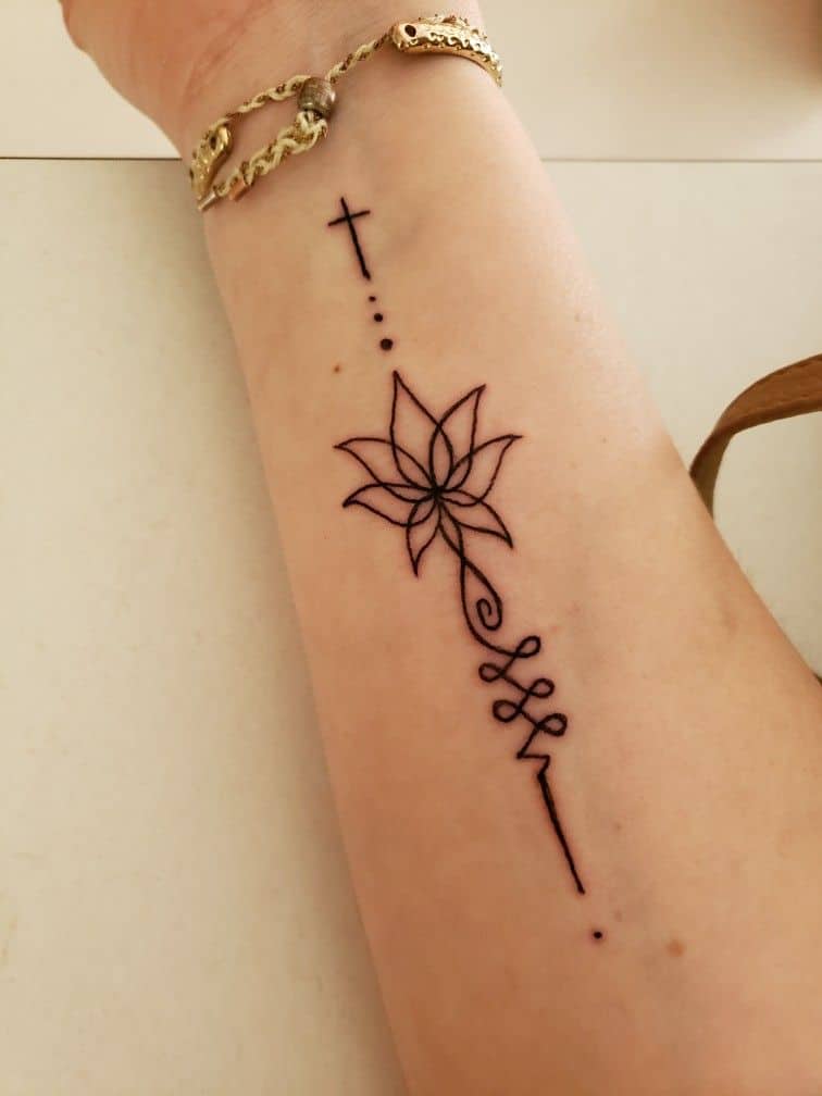 Unalome and lotus tattoo on the forearm with a small cross, symbolizing spiritual growth, faith, and the path to enlightenment.
