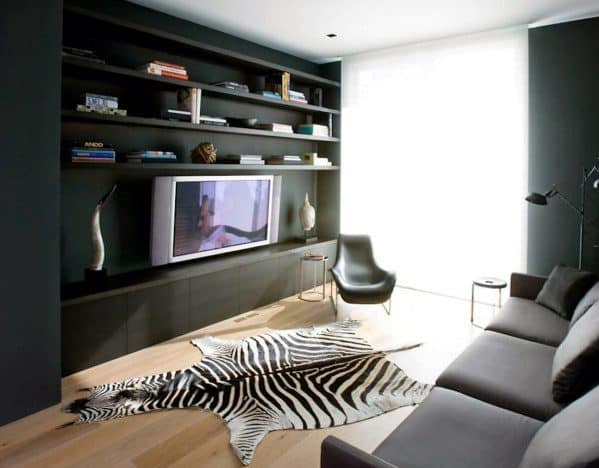 Modern man cave with a zebra rug, wall-mounted TV, dark shelves, and sleek furniture