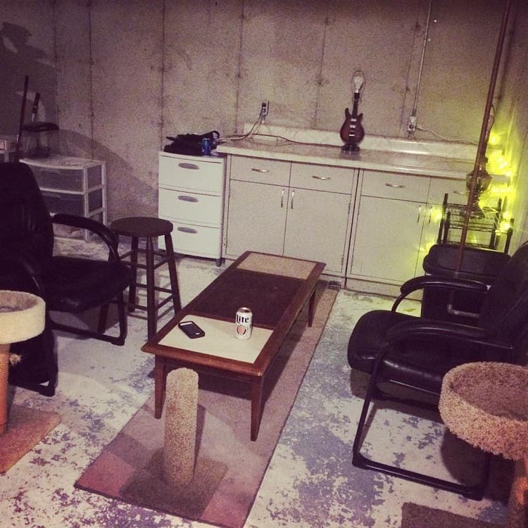 small basement with cabinets black lounge chairs wood table 