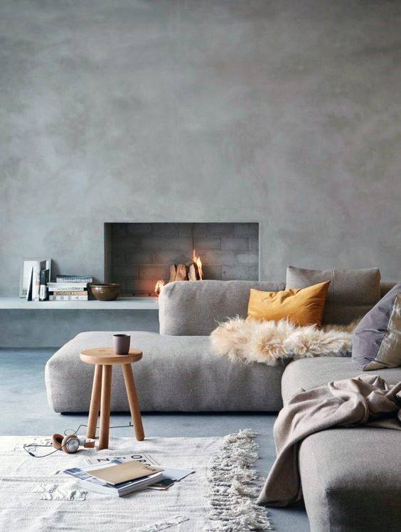 Minimalist living room featuring a sleek concrete fireplace, cozy sectional sofa, and warm accent pillows.