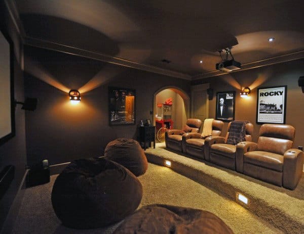 Dimly lit home theater with leather recliners, wall posters, bean bags on a carpeted floor