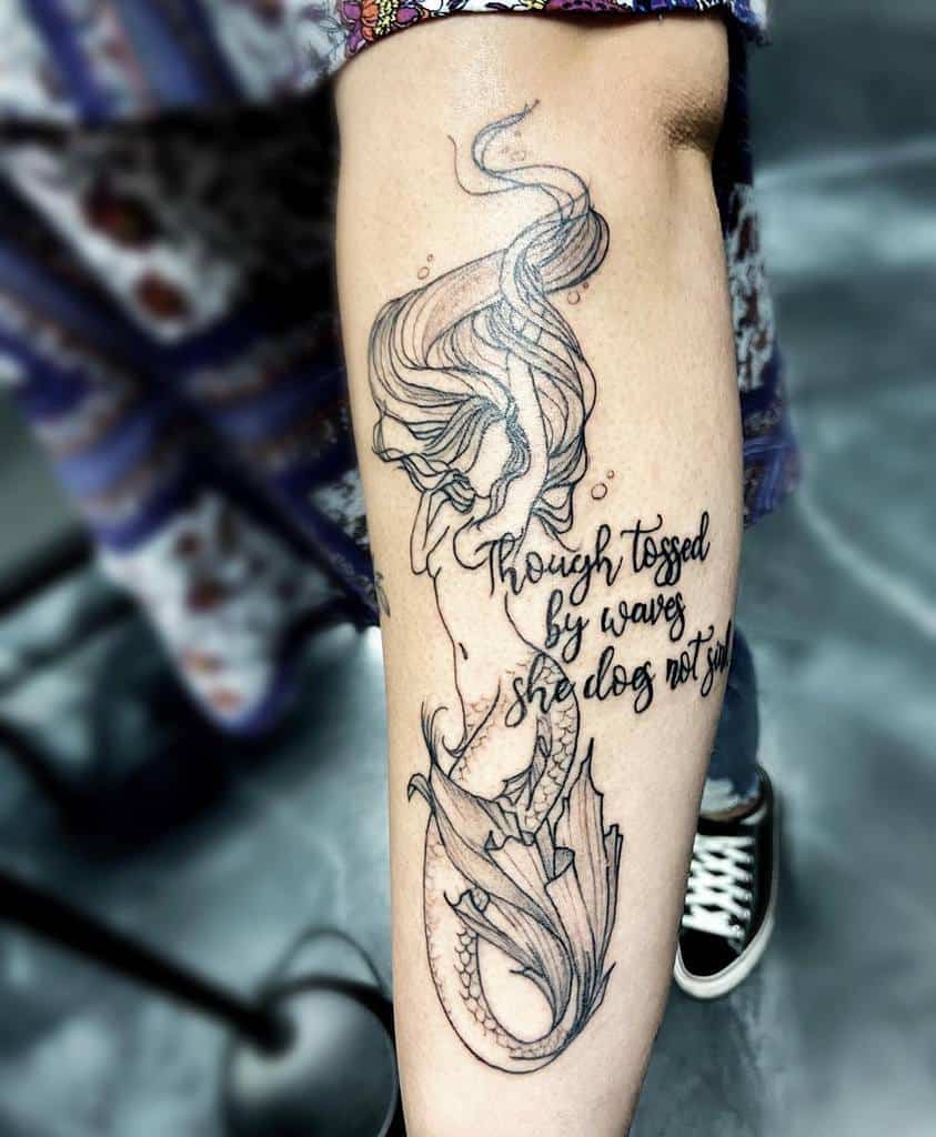 Elegant black line tattoo of a mermaid with flowing hair, detailed tail, and the quote 'Though tossed by waves, she does not sink.'