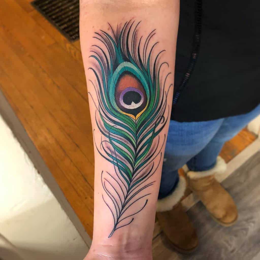 Vibrant peacock feather tattoo on the forearm, featuring bold green, blue, and purple hues with fine linework and intricate shading.