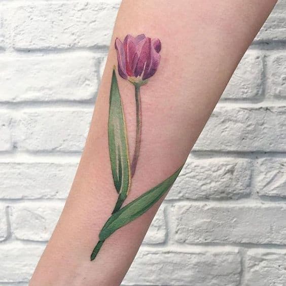 Tattoo of a purple tulip with green leaves on a forearm