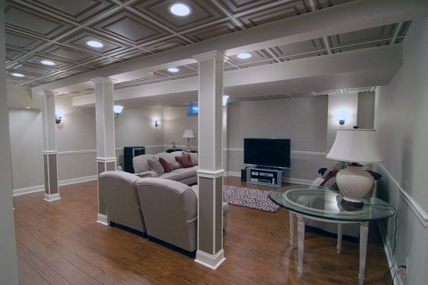 Basement with white coffered ceiling, recessed lighting, columns, and cozy seating area.