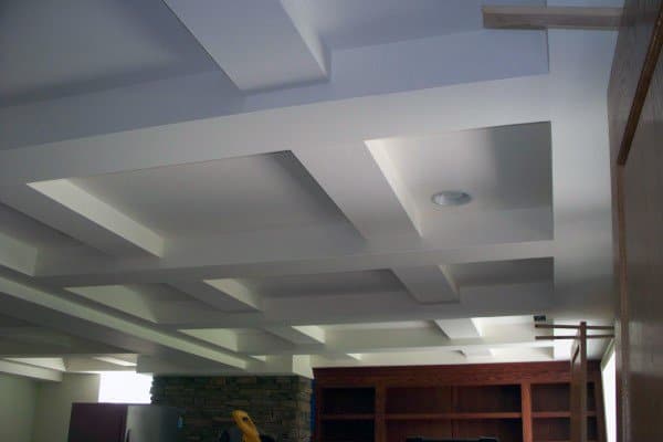 Basement with white coffered ceiling, recessed lighting, and built-in shelving.