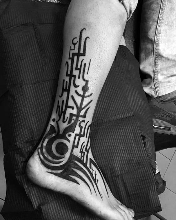 Blast over abstract tribal tattoo design in black ink, covering leg and foot