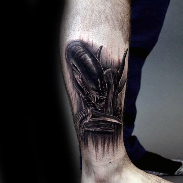 Dark and intense Xenomorph tattoo on lower leg, featuring the alien emerging with sharp claws and dripping shadow-like effect.