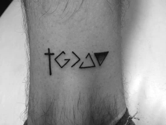 This minimalist tattoo features the "God is greater than the highs and lows" symbol seamlessly integrated with a cross, representing a blend of faith, resilience, and spiritual balance