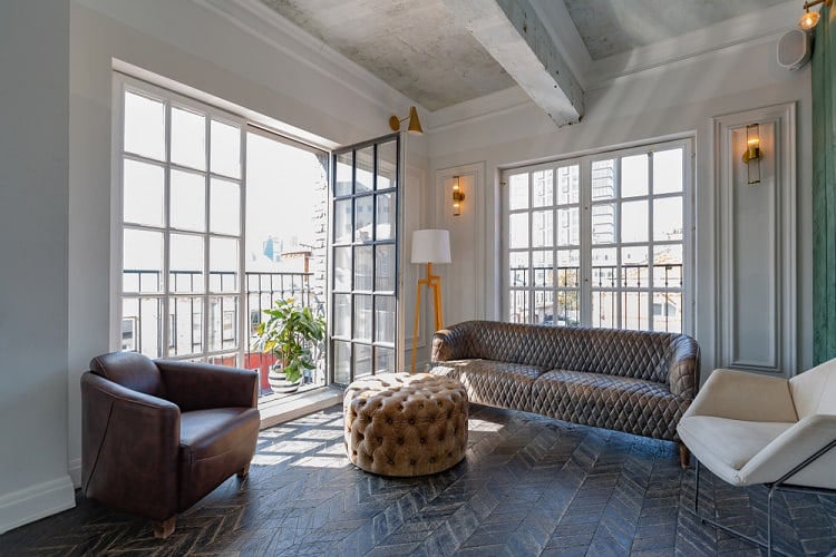 A luxurious guest room with an unfinished concrete ceiling, large windows offering stunning city views, and elegant furniture, creating a modern and sophisticated atmosphere