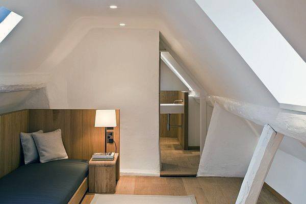 Cozy attic room with a daybed, lamp, wooden accents, and a wash area nestled under sloped ceilings