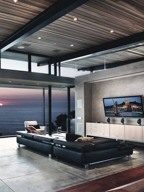 Luxury living room with ocean view, black leather sectional, and modern decor.