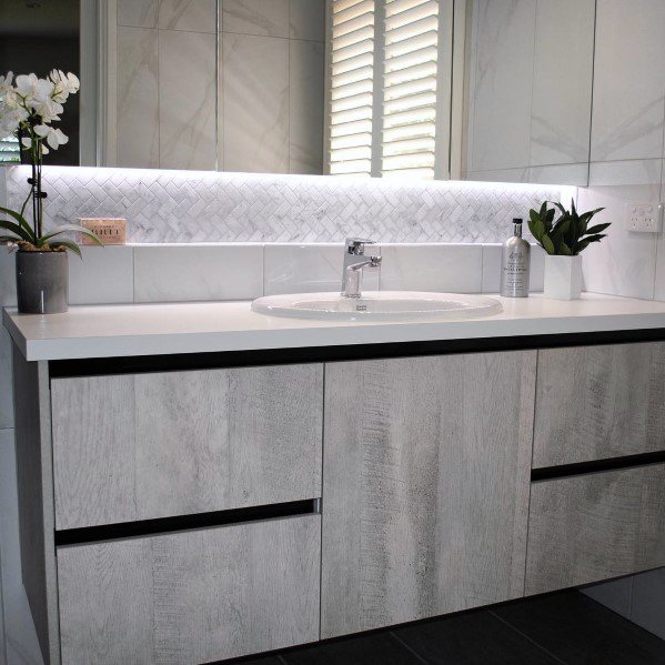 Modern bathroom with floating vanity, light wood cabinets, and LED backlit mirror.