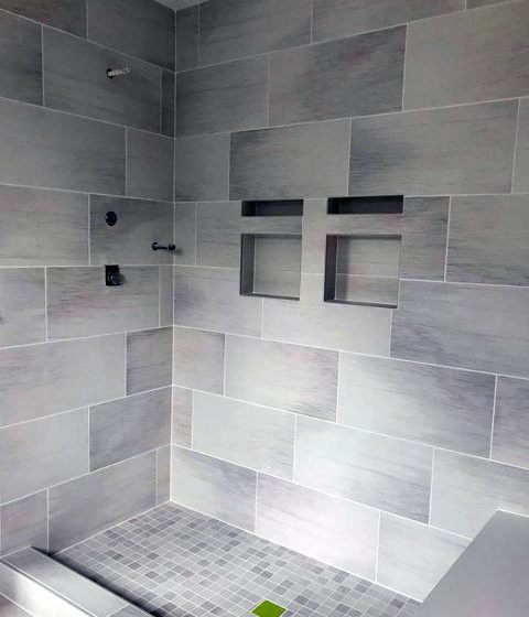 Light travertine tile shower with built-in niches and small square mosaic tile floor.