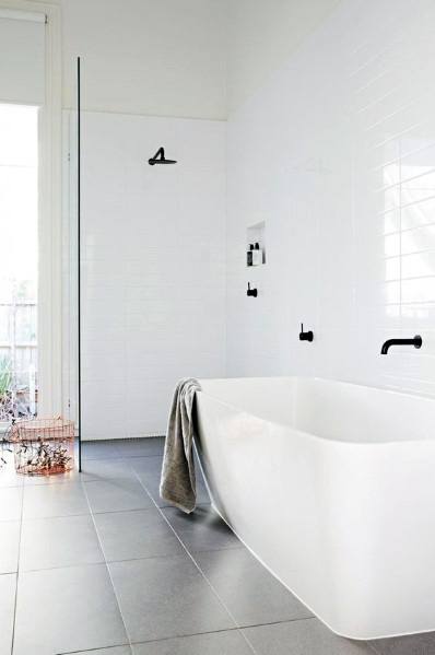 Minimalist bathroom with freestanding tub, white subway tile wall, and black fixtures.