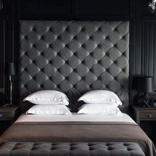 Luxurious black bedroom with tufted headboard, white bedding, and elegant bedside decor.