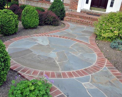 Circular walkway bordered by bricks, surrounded by green bushes