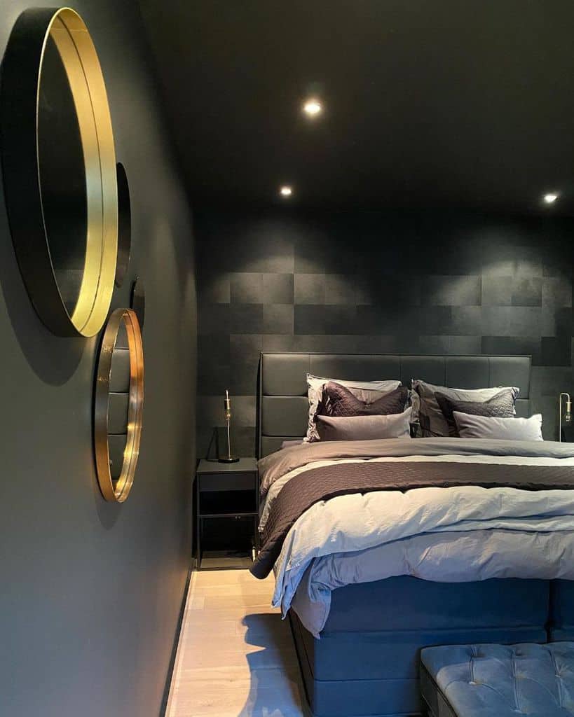 Modern bedroom with dark walls, a bed with gray linens, circular mirrors, and soft lighting