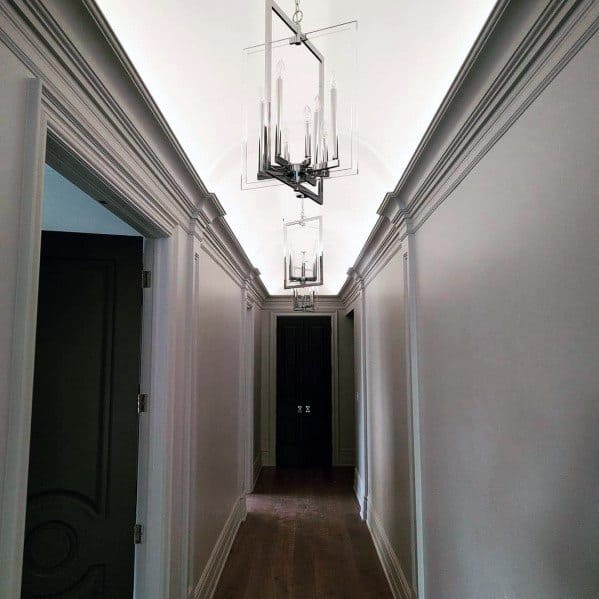 Sophisticated hallway with luxurious crown molding lighting and elegant hanging fixtures, creating a refined atmosphere
