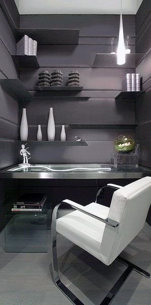 Sleek modern office with black walls, floating shelves, vases, a chair, and a minimalist desk lamp