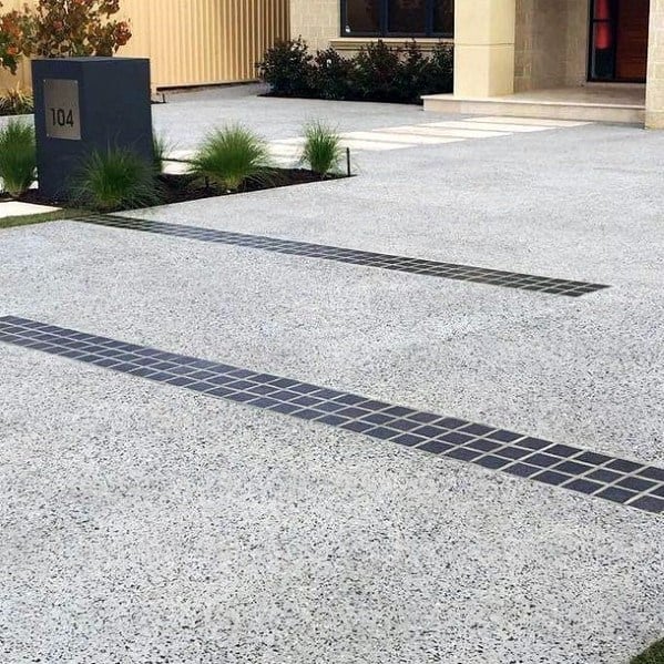 Exposed aggregate driveway with black tile strips for a modern touch.