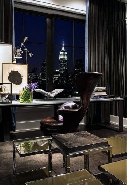 Luxurious office with a leather chair, book, and flowers on the desk, overlooking a cityscape at night