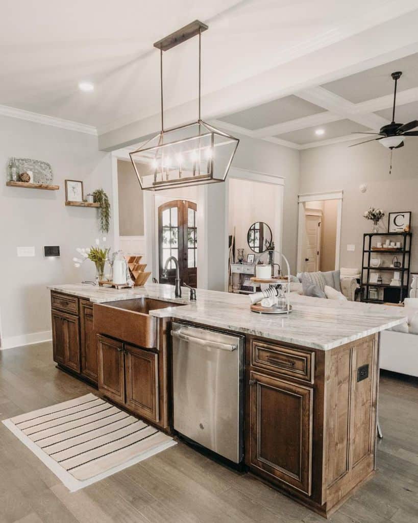 Farmhouse-style kitchen with a rich wooden island, marble countertop, apron-front sink, and a modern rectangular pendant light.