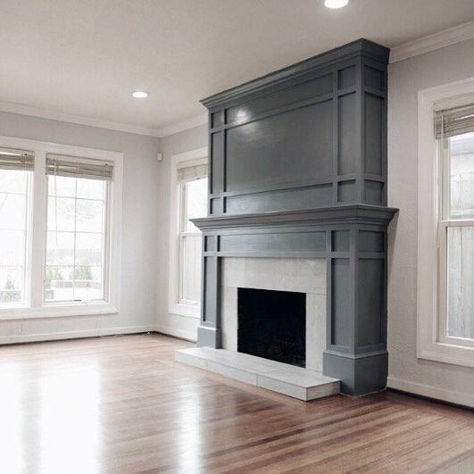 Large gray fireplace mantel with paneled details, white marble surround, and elevated hearth.