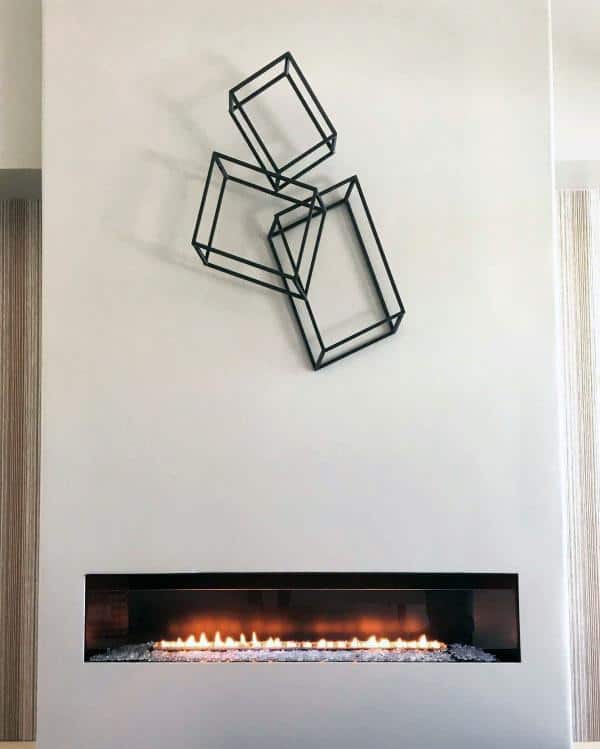 Minimalist linear gas fireplace with a black frame set in a smooth white wall.