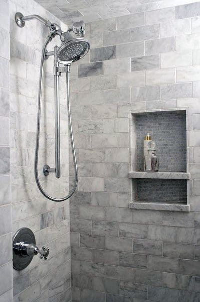 Gray marble shower with handheld showerhead and built-in niche shelving.