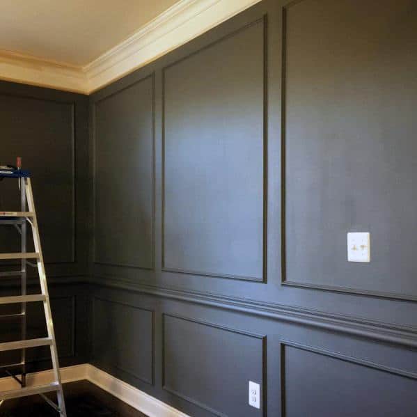 Room with dark green paneled walls, a step ladder, chair rail, and crown molding along the ceiling