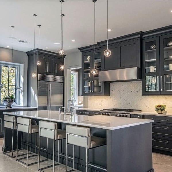 Luxury grey kitchen with white countertops, pendant lights, and stainless steel appliances.