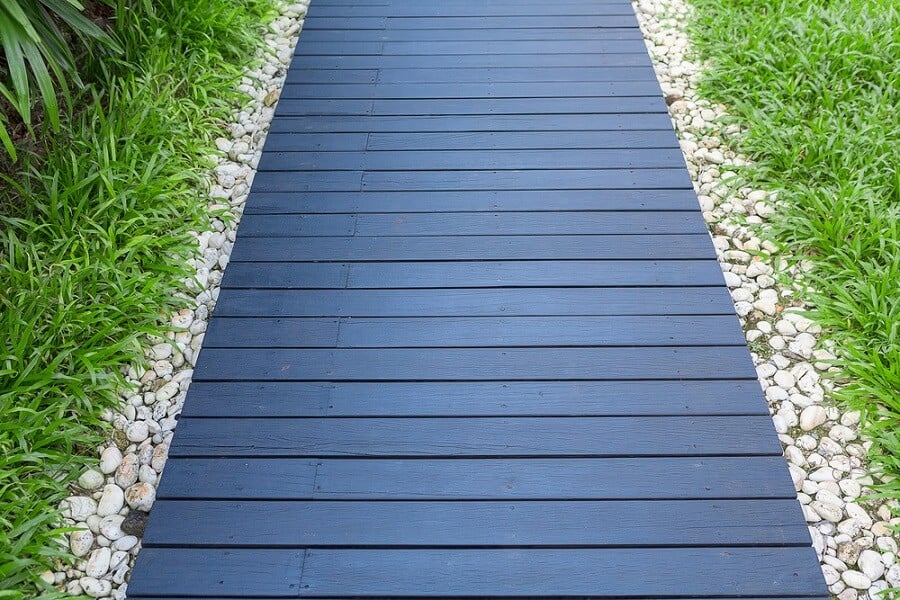 Walkway of wooden planks with white stones surrounded by green grass