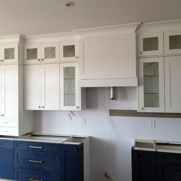 Luxury kitchen featuring elegant crown molding, white upper cabinets, dark blue lower cabinets, and chic hardware details
