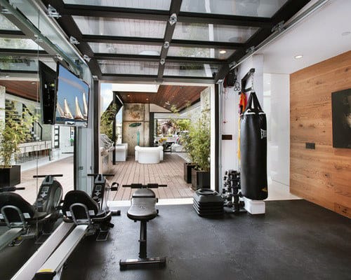 Modern home gym with equipment, punching bag, and glass doors opening to a patio with outdoor seating